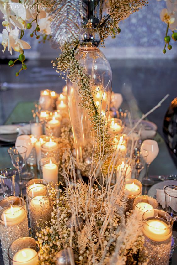 a winter wonderland wedding tablescape with frozen branches and baby's breath, floating candles is enchanting