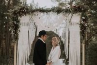 a woodland boho wedding arch with macrame, greenery and white blooms is a lovely idea for a winterwedding