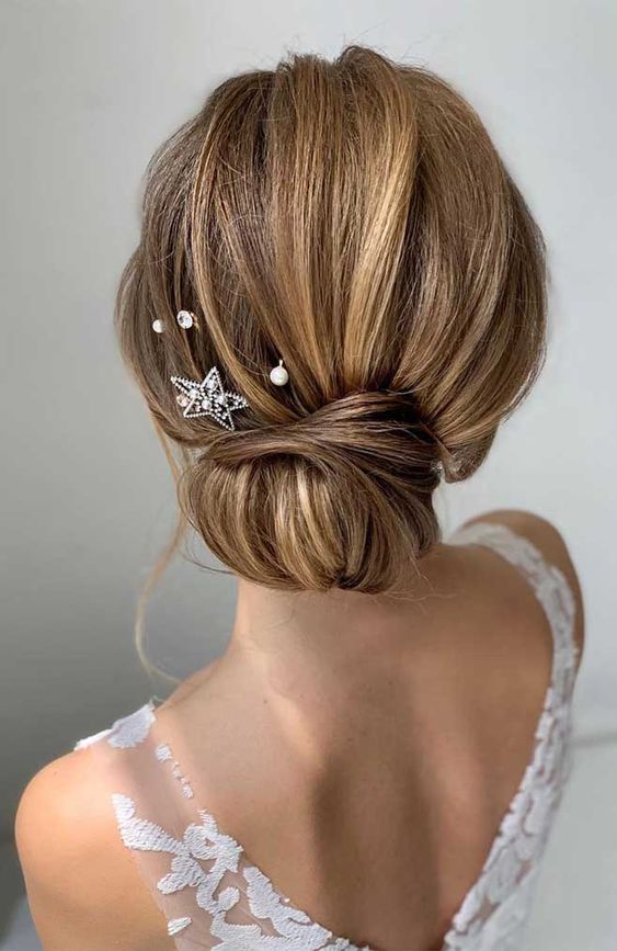 a wrapped low bun with a bump on top and pearl and rhinestone hairpins plus a star hairpin is a lovely idea for any bride