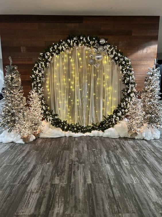 an adorable winter wonderland wedding ceremony space with a round light wedding arch and silver flocked Christmas trees