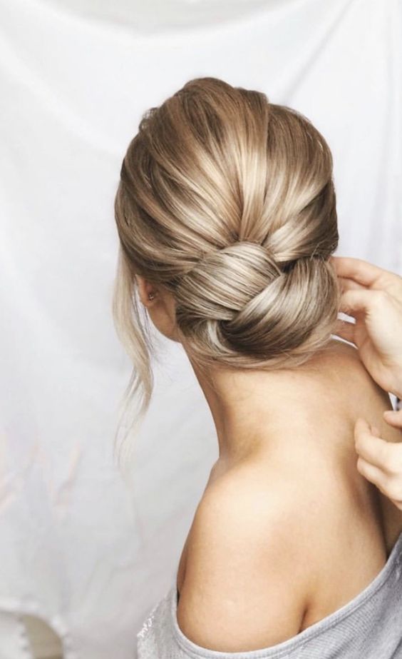 an elegant low chignon bun with a bump on top and face-framing hair is a lovely idea for a modern bride