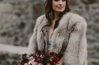 an embellished wedding dress paired with a grey faux fur cover up for a chic and refined winter bridal look that inspires