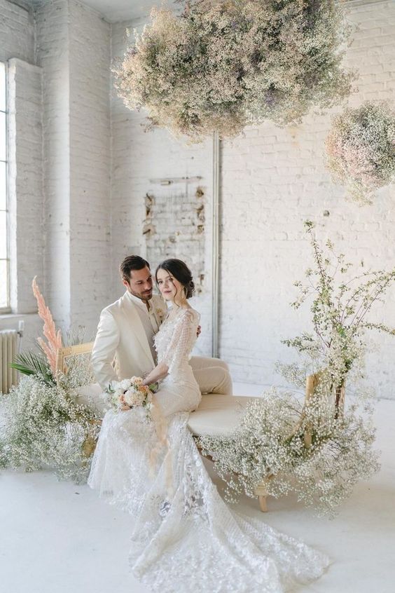 an ethereal wedding lounge with baby's breath overhead installations and matching bench decor is amazing