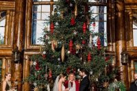 an oversized Christmas tree with gold and red ornaments as a backdrop for a Christmas wedding