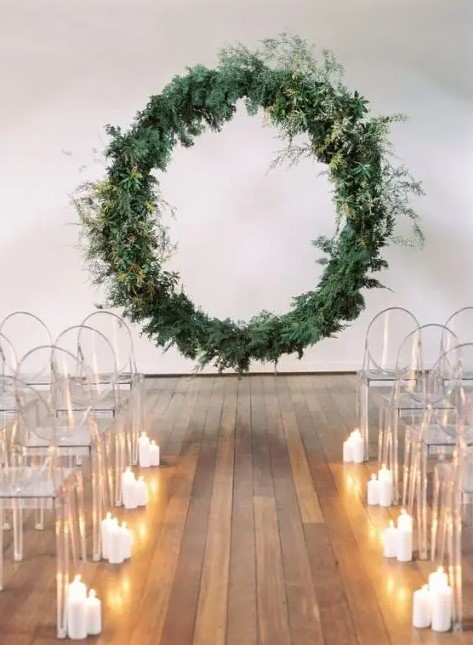 An oversized round greenery wedding arch floating in the air, ghost chairs and candles for an ultra modern wedding