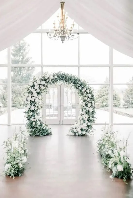 textural greenery and white blooms plus a matching round wedding arch for creating a romantic and beautiful winter wedding space
