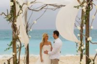03 driftwood wedding arch decorated with white fabric and flowers for a beach wedding