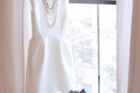10 white sleeveless mini gown with a scallop edge, a statement necklace and blue heels