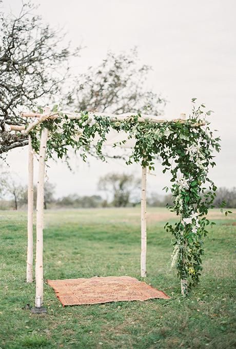 earthy and rustic chuppah with draped fabric ceiling and dark foliage