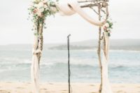 13 rough tree branch arch with pastel fabric and flowers on the corner
