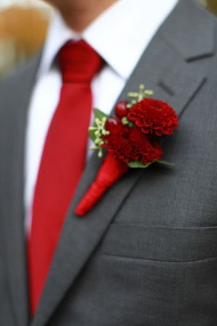 a crimson red tie and dahlia boutonniere with a dark grey suit