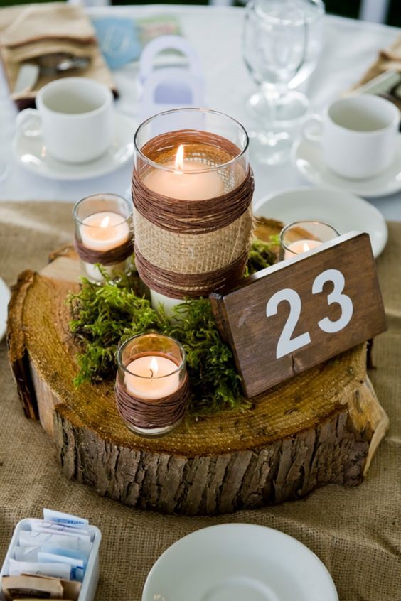 wood slice centerpiece with moss and candles and table numbers on a wood piece