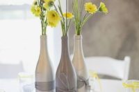21 silver and grey bottles with sunny yellow flowers for a centerpiece