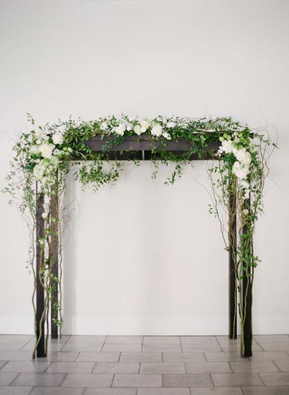 dark wood arbor decorated with white flowers and greenery