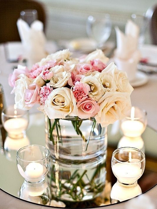 a round mirror, glass candle holders and pastel flowers