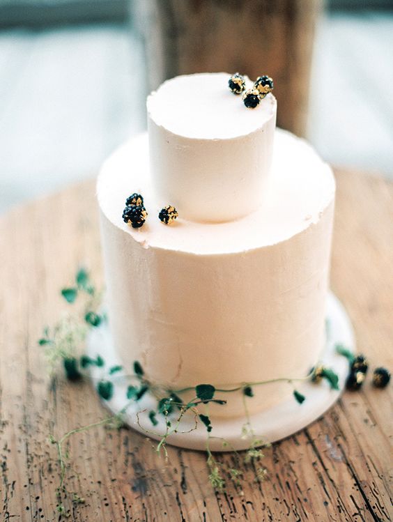 simple frosted cake decorated with berries and greenery