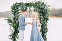 a beautiful winter wedding arch of evergreens with fake icicles hanging gown for a frozen feel