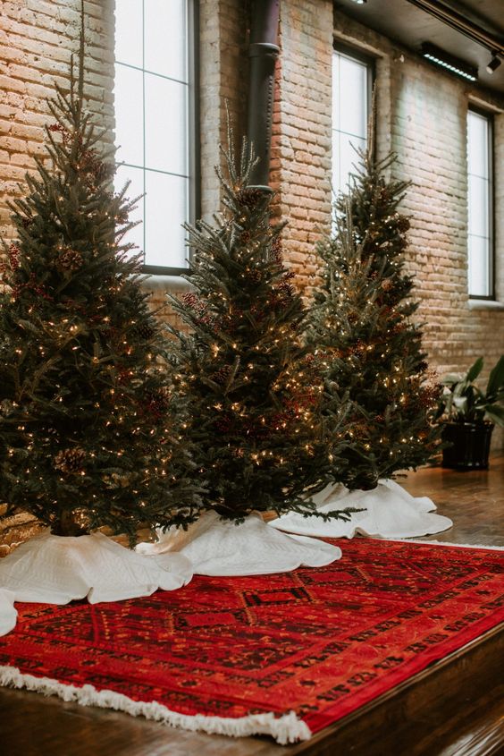 a bold wedding backdrop with Christmas trees and lights styled with skirts is a cool idea for a wedding