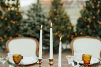 a chic lush table runner of evergreens, candles, tall and thin candles in a candelabra, vintage books for a Christmas wedding