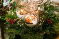 a cozy Christmas centerpiece of evergreens, berries, candle lanterns with fake snow