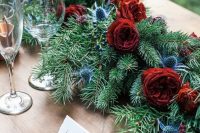 a gorgeous wedding table runner of evergreens, red roses and thistles is a fresh take on classics for a winter wedding