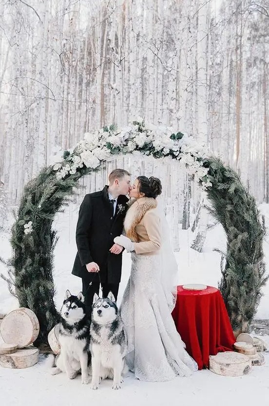 a round wedding arch of evergreens and with lots of white blooms on top is a fantastic idea for a snowy Christmas wedding