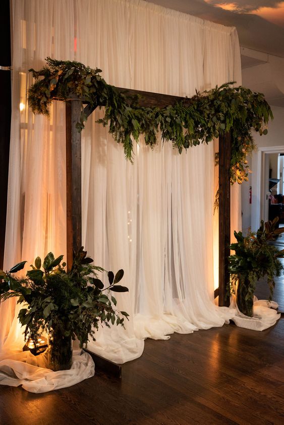 a rustic winter wedding arch with evergreens and greenery and some arrangements is a cool idea for a wedding