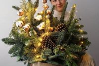 a super lush and bold Christmas wedding arrangement of evergreens, pinecones, cotton and lights is wow