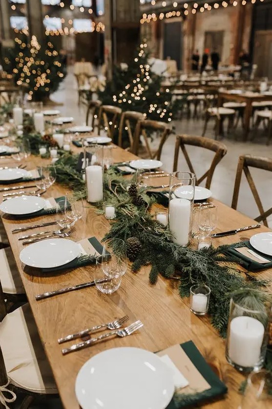 an evergreen and pinecone table garland with pillar candles is a lovely rustic decoration for a fall or winter wedding