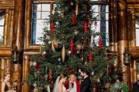 an oversized Christmas tree with gold and red ornaments as a backdrop for a Christmas wedding