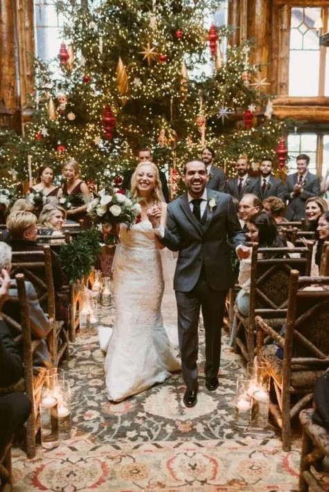 an oversized Christmas tree with lots of lights and gold and red ornaments is perhaps one of the best wedding backdrops ever