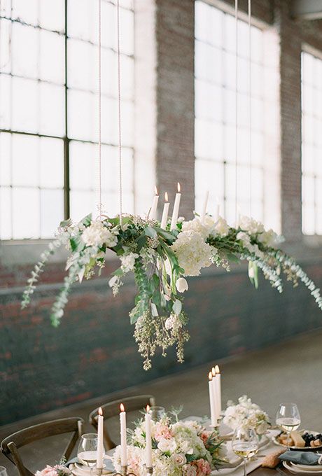 ferns and assorted white flowers suspended above tables in this warehouse venue add a touch of romance