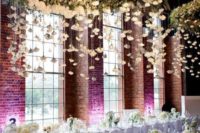 giant white flower chandelier with hanging flowers from above for an all-white modern reception