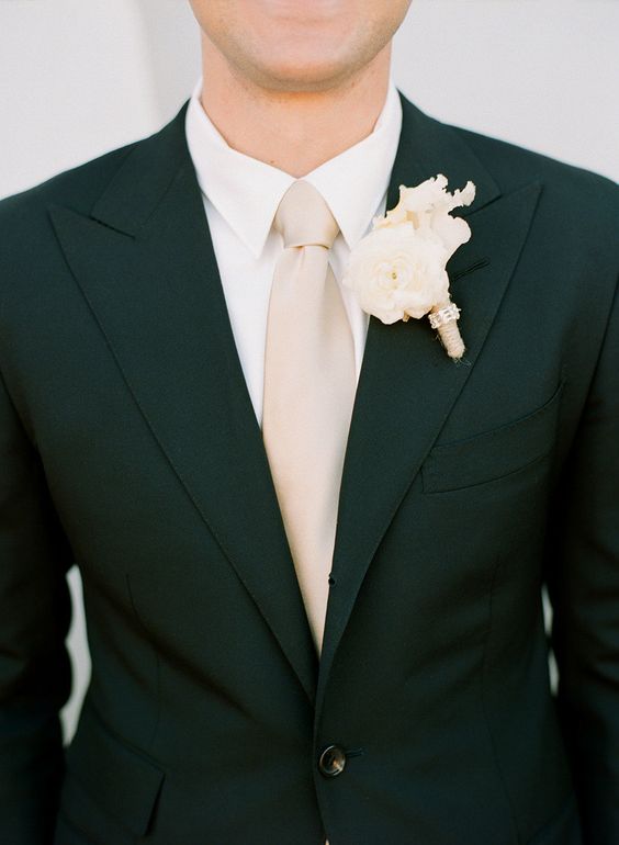 a black suit, a blush tie and an ivory shirt and boutonniere