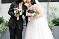 one bride rocking a sexy black pantsuit and heels, the second bride wearing a wedding ballgown with an embellished bodice and a veil