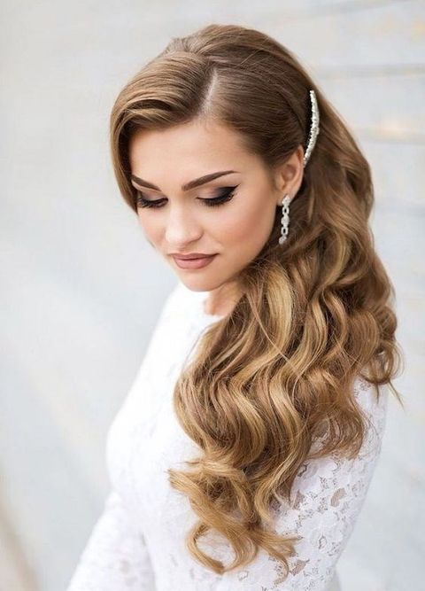 long wavy side swept hair accented with a shiny rhinestone hairpiece is a gorgeous idea that isn't difficult to recreate