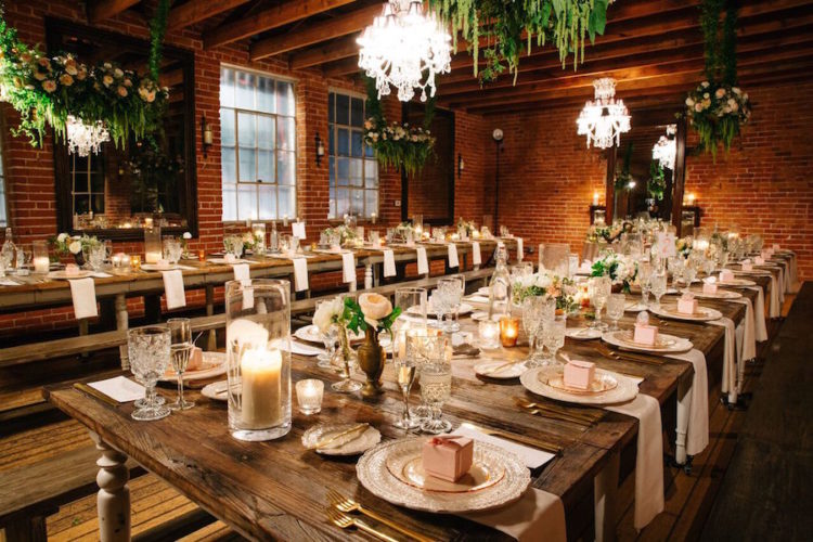 The reception was lit with candles and refined chandeliers, rustic wooden tables and benches looked contrasting with brick walls