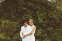 an all-white bridal pantsuit with sneakers and a romantic lace mermaid wedding dress with a train are a cool combo for a couple look