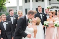 12 groomsmen in black tuxedos and bridesmaids in blush gowns