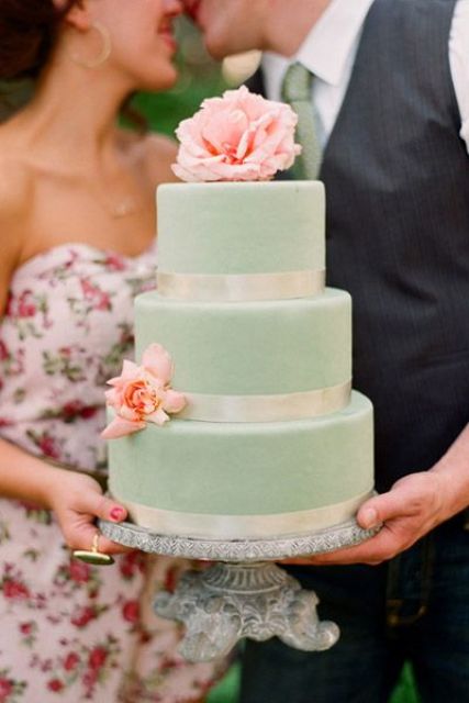 a mint wedding cake with ivory ribbon and fresh peach flowers