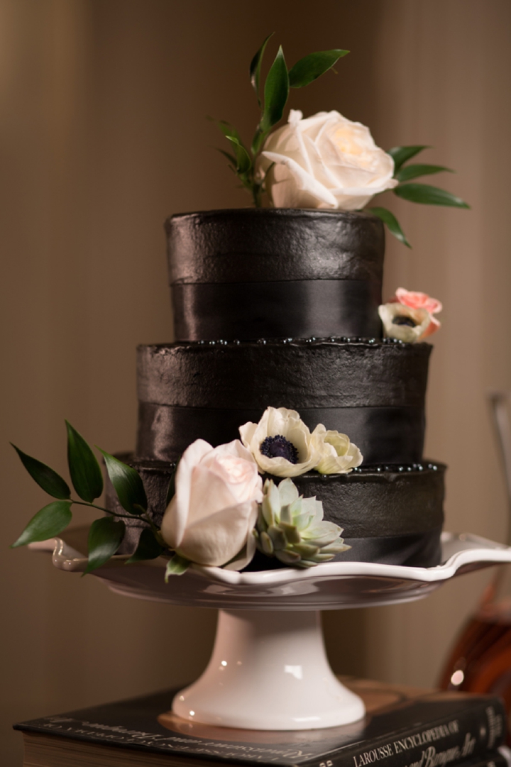 black wedding cake decorated with blush flowers