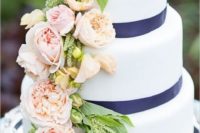 27 a white cake with navy ribbon and blush flowers