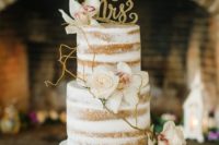 32 dirty frosted wedding cake decorated with flowers, branches and glitter toppers