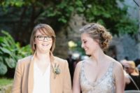 a glitzy embellished strap wedding dress with a V-neckline, a tan blazer, a white top and black pants for a chic couple look