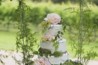 43 semi naked wedding cake with blush flowers and a lot of greenery on a hanging display