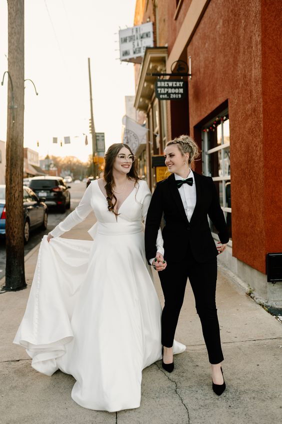 a black tuxedo with black shoes, a dreamy plain wedding ballgown with a plunging neckline and long sleeves plus a train
