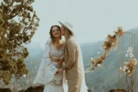 a boho lace separate with a crop top and bell sleeves and atrumpet skirt, a beige pantsuit, white sneakers and a hat for a boho wedding