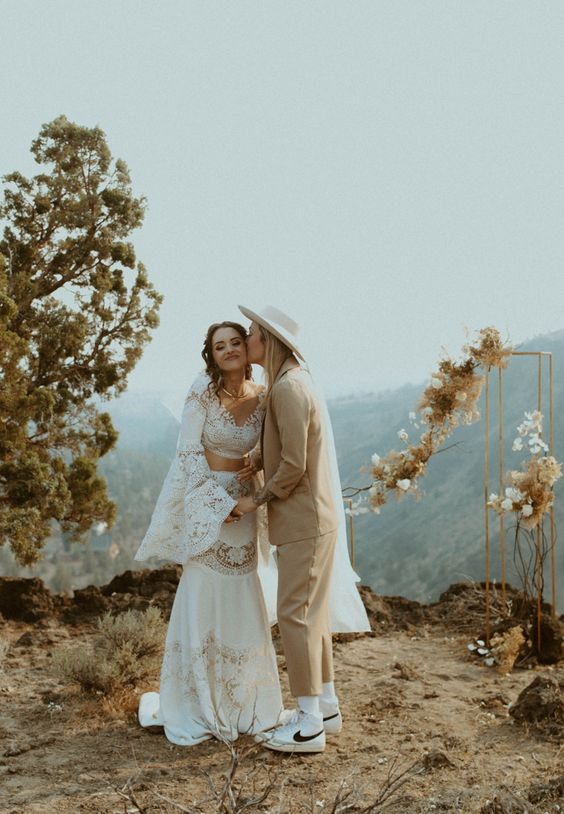 a boho lace separate with a crop top and bell sleeves and atrumpet skirt, a beige pantsuit, white sneakers and a hat for a boho wedding
