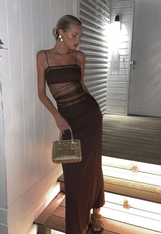 a brown maxi dress with spaghetti straps and sheer parts, brown sandals and a gold bag plus statement earrings