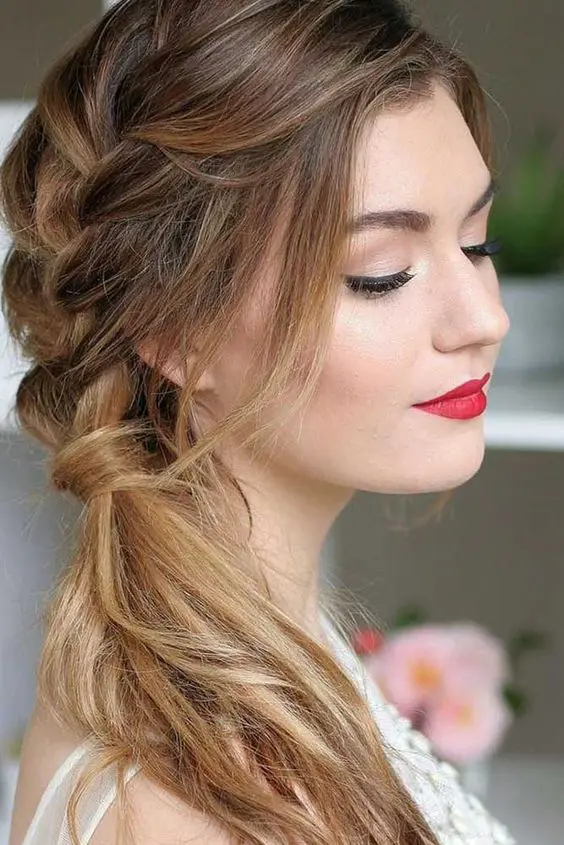a lovely side swept hairstyle with a side braid coming into a ponytail, with face-framing locks and a slight ombre touch